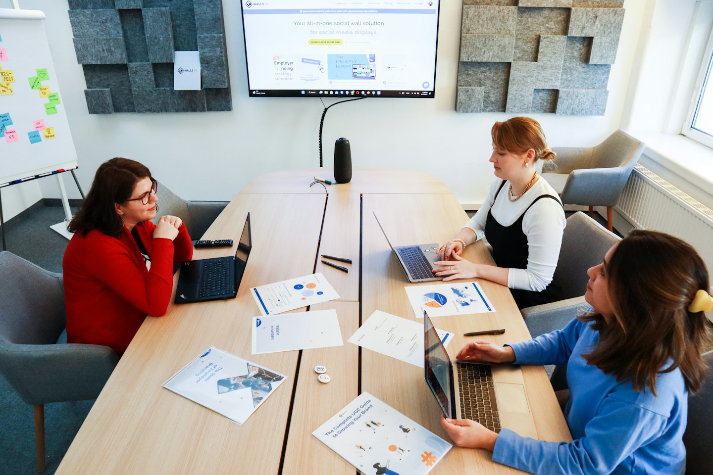 Drei Frauen arbeiten an einem Tisch mit Laptops im Büro zusammen.