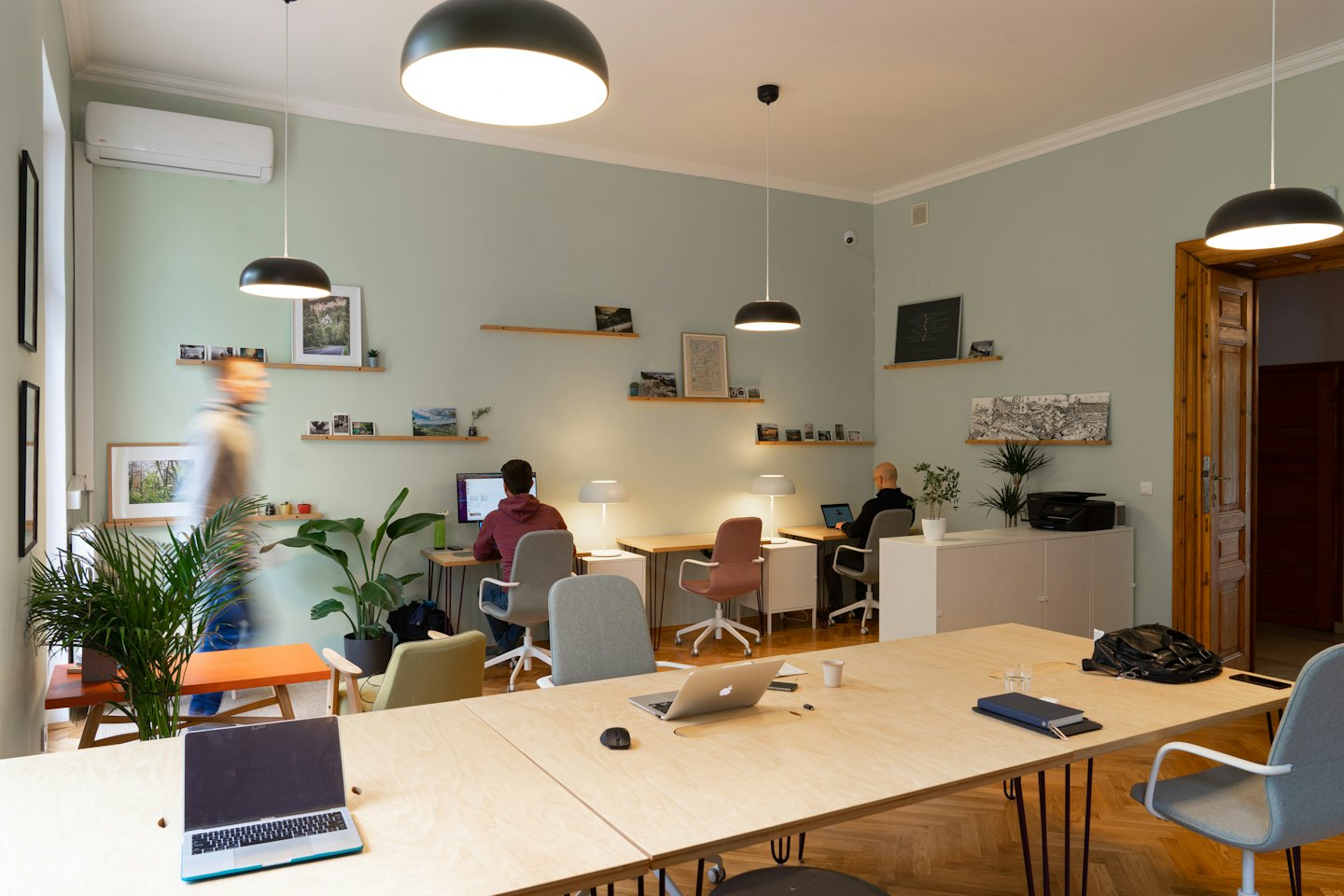 Drei Personen arbeiten an Schreibtischen in einem modernen Coworking-Büro.